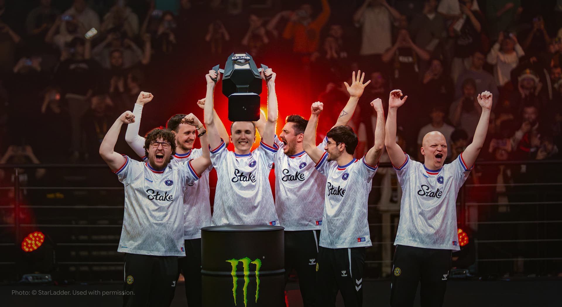 Esports team celebrating with a trophy on stage
